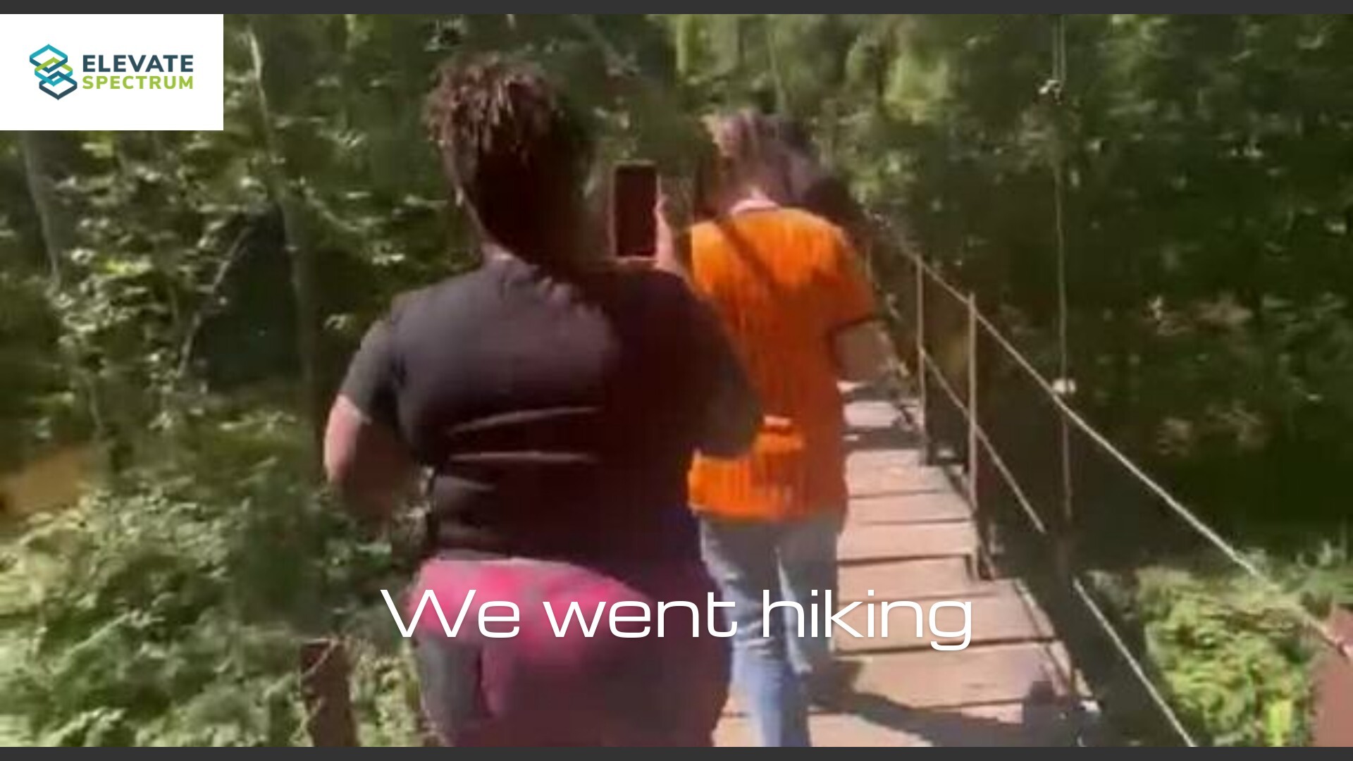 Adults walking a wooded trail on a clear afternoon